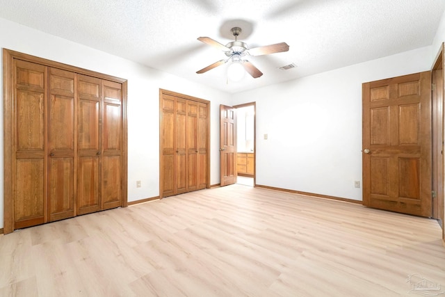 unfurnished bedroom with ceiling fan, multiple closets, a textured ceiling, and light hardwood / wood-style flooring