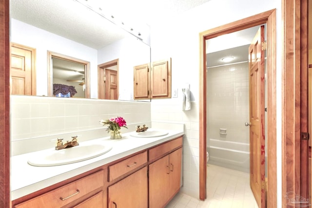 full bathroom with decorative backsplash, vanity, a textured ceiling, tiled shower / bath combo, and toilet