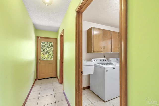 laundry area featuring cabinets, a textured ceiling, light tile patterned floors, and separate washer and dryer