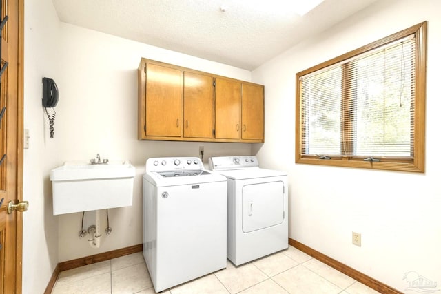 laundry room with cabinets, separate washer and dryer, a textured ceiling, and light tile patterned floors