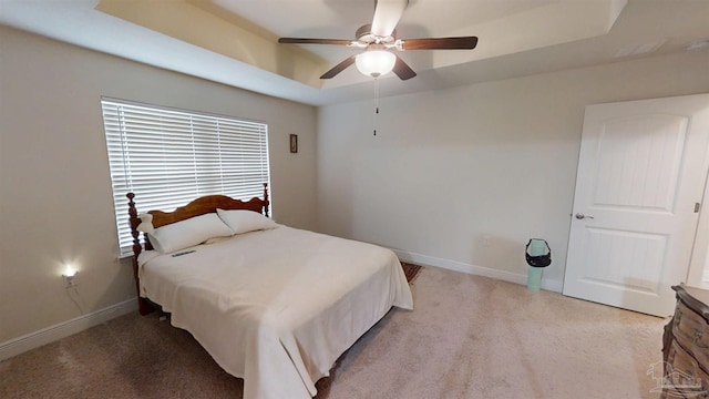 bedroom with baseboards, a tray ceiling, a ceiling fan, and light colored carpet