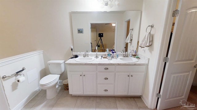 bathroom featuring toilet, double vanity, a sink, and tile patterned floors