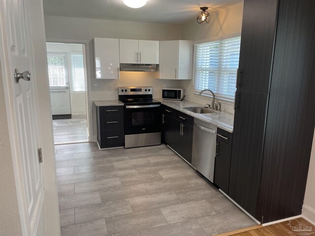 803 Pickens Ave, Pensacola, FL 32503 - kitchen featuring appliances with stainless steel finishes, a sink, under cabinet range hood, white cabinetry, and light countertops