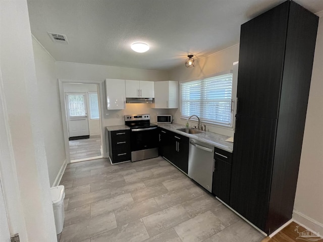 803 Pickens Ave, Pensacola, FL 32503 - kitchen with appliances with stainless steel finishes, a sink, under cabinet range hood, light countertops, and dark cabinets