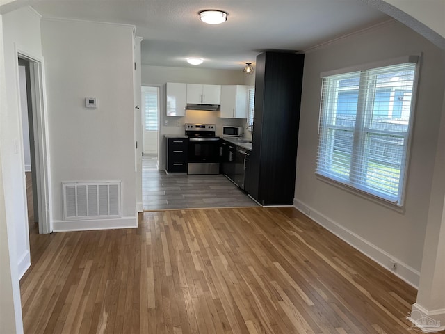 803 Pickens Ave, Pensacola, FL 32503 - kitchen with stainless steel appliances, under cabinet range hood, light wood-type flooring, baseboards, and white cabinetry