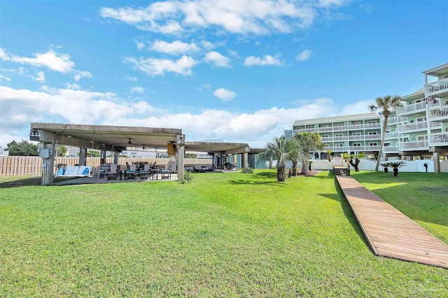 view of property's community with a lawn, a patio area, fence, and a pergola