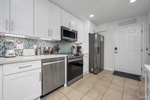 kitchen featuring light tile patterned floors, stainless steel appliances, tasteful backsplash, light countertops, and white cabinetry