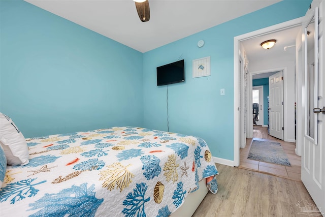 bedroom featuring baseboards, a ceiling fan, and light wood-style floors