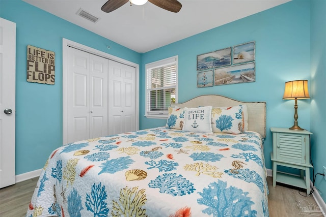 bedroom featuring wood finished floors, a ceiling fan, visible vents, baseboards, and a closet