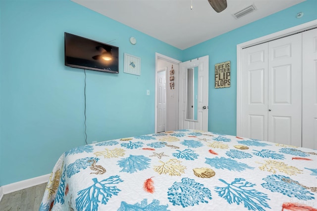 bedroom with a closet, visible vents, a ceiling fan, wood finished floors, and baseboards