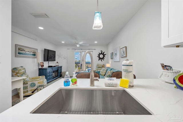 details featuring visible vents, white cabinets, ceiling fan, hanging light fixtures, and a sink