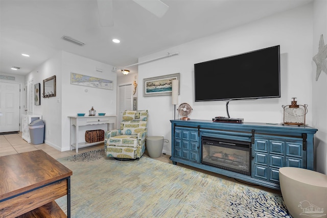 living area with light tile patterned flooring, a glass covered fireplace, visible vents, and recessed lighting