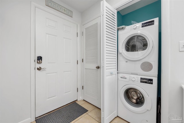 clothes washing area featuring laundry area, stacked washing maching and dryer, and light tile patterned floors