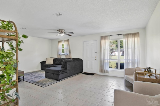 living room featuring ceiling fan, a textured ceiling, a healthy amount of sunlight, and light tile patterned floors