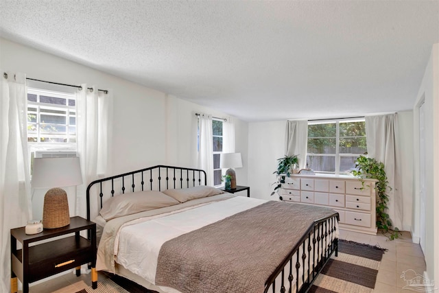 tiled bedroom with a textured ceiling and multiple windows