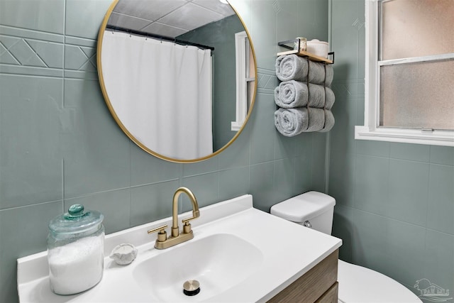 bathroom with toilet, vanity, tile walls, and backsplash