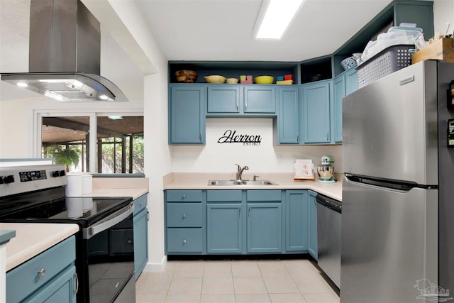 kitchen with wall chimney exhaust hood, sink, light tile patterned floors, blue cabinetry, and appliances with stainless steel finishes