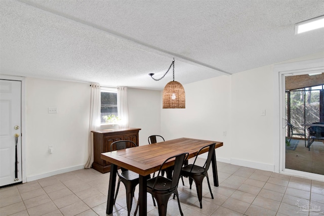 tiled dining room featuring a textured ceiling and a healthy amount of sunlight