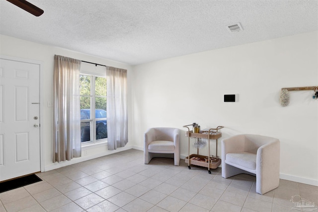 sitting room with light tile patterned flooring, a textured ceiling, and ceiling fan