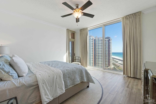 bedroom with hardwood / wood-style flooring, ceiling fan, a water view, and multiple windows