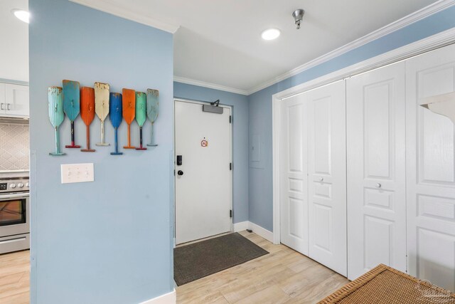 foyer with light wood-type flooring and ornamental molding