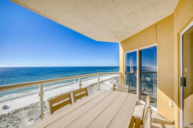 balcony with a water view and a view of the beach