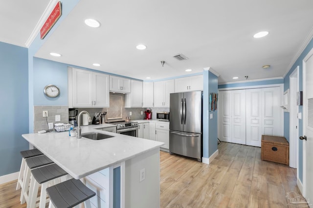 kitchen with white cabinets, appliances with stainless steel finishes, light hardwood / wood-style flooring, and sink