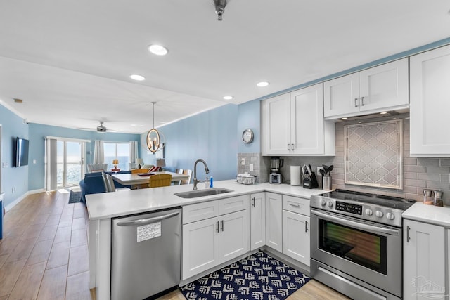 kitchen featuring white cabinetry, sink, kitchen peninsula, appliances with stainless steel finishes, and light wood-type flooring