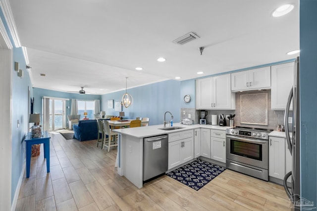 kitchen featuring kitchen peninsula, white cabinetry, sink, and stainless steel appliances