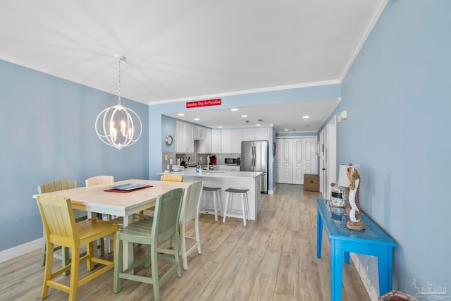 dining space featuring an inviting chandelier, ornamental molding, and light wood-type flooring