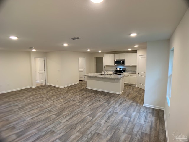 kitchen featuring stainless steel appliances, a sink, recessed lighting, open floor plan, and white cabinetry
