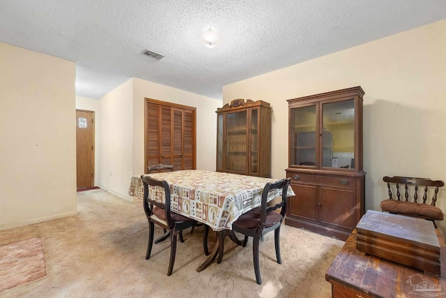 carpeted dining space featuring a textured ceiling