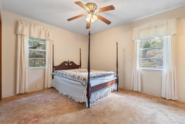 carpeted bedroom with a textured ceiling, multiple windows, and ceiling fan