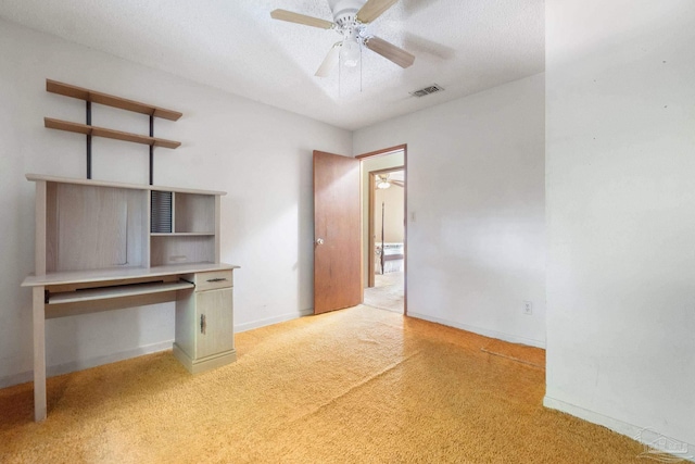 interior space featuring ceiling fan, built in desk, a textured ceiling, and light carpet