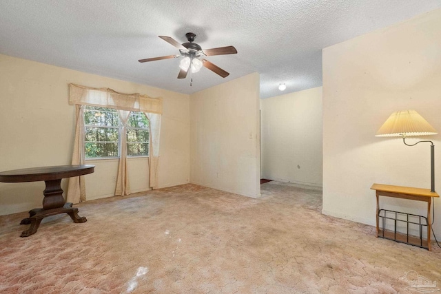 unfurnished living room with a textured ceiling, light colored carpet, and ceiling fan