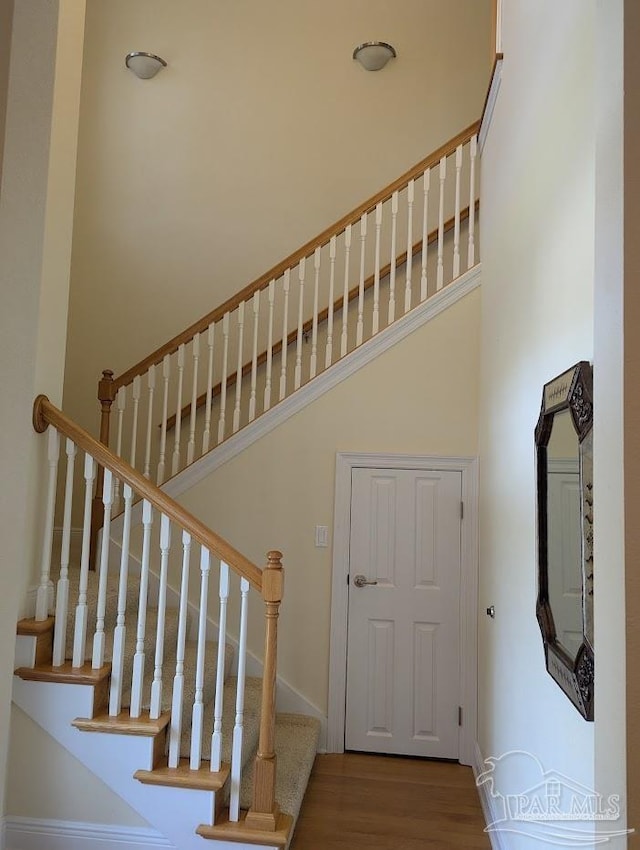 staircase with a high ceiling and hardwood / wood-style flooring