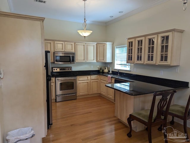 kitchen featuring a breakfast bar, light hardwood / wood-style flooring, stainless steel appliances, hanging light fixtures, and sink