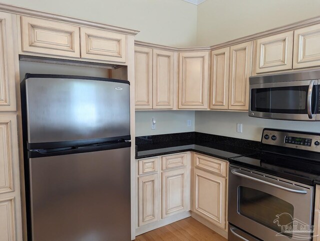 kitchen with appliances with stainless steel finishes, cream cabinetry, and light wood-type flooring