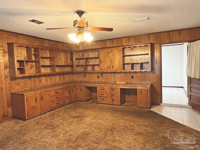 unfurnished office featuring wood walls, built in desk, and light carpet