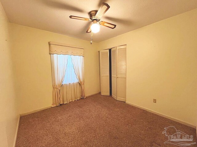 unfurnished bedroom with ceiling fan, a closet, and carpet floors