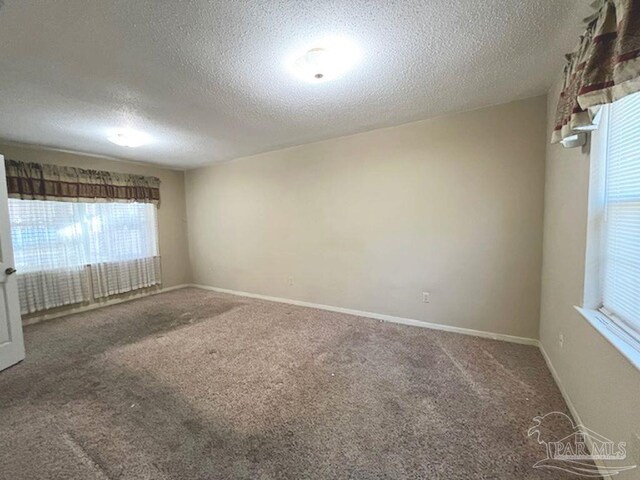 carpeted spare room featuring a textured ceiling