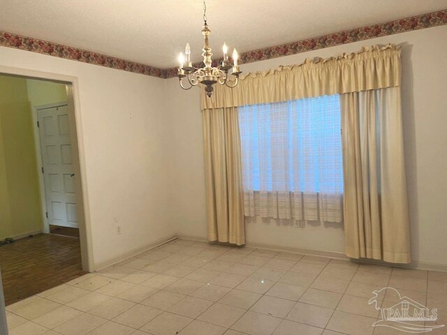 tiled empty room with an inviting chandelier