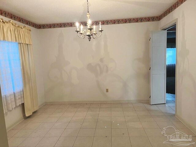 tiled empty room with an inviting chandelier