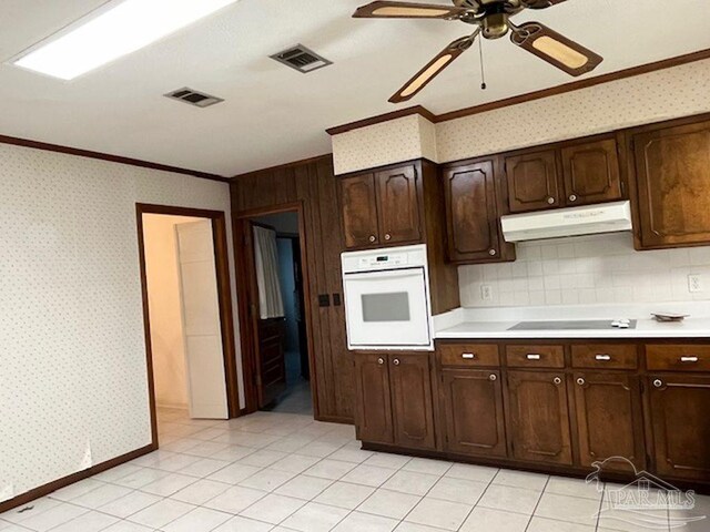 kitchen featuring white oven, dark brown cabinetry, light tile patterned flooring, and decorative backsplash