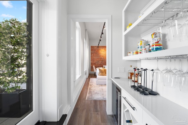 bar featuring wine cooler, a dry bar, brick wall, and dark wood-type flooring