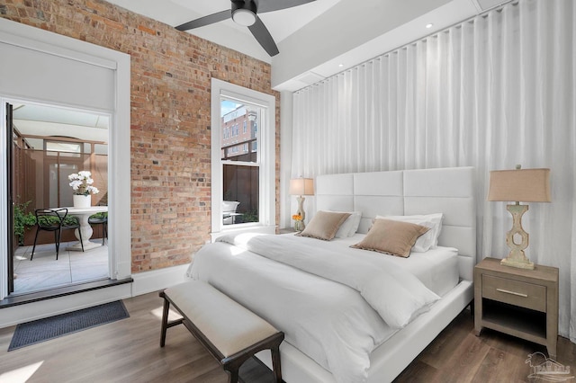 bedroom featuring wood-type flooring, brick wall, and ceiling fan