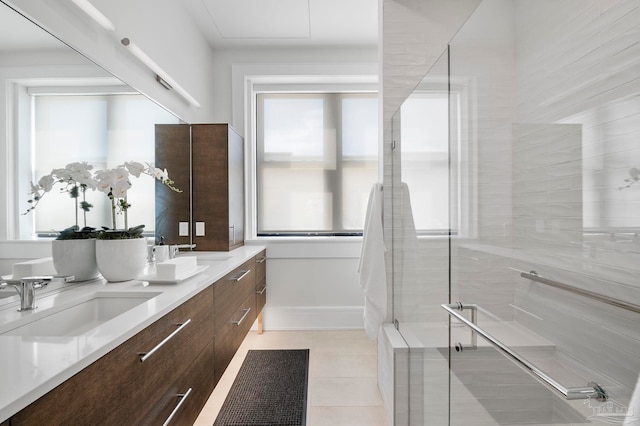 bathroom with tile patterned flooring, baseboards, double vanity, a stall shower, and a sink