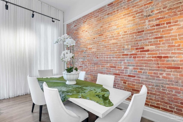 dining space with brick wall and wood finished floors