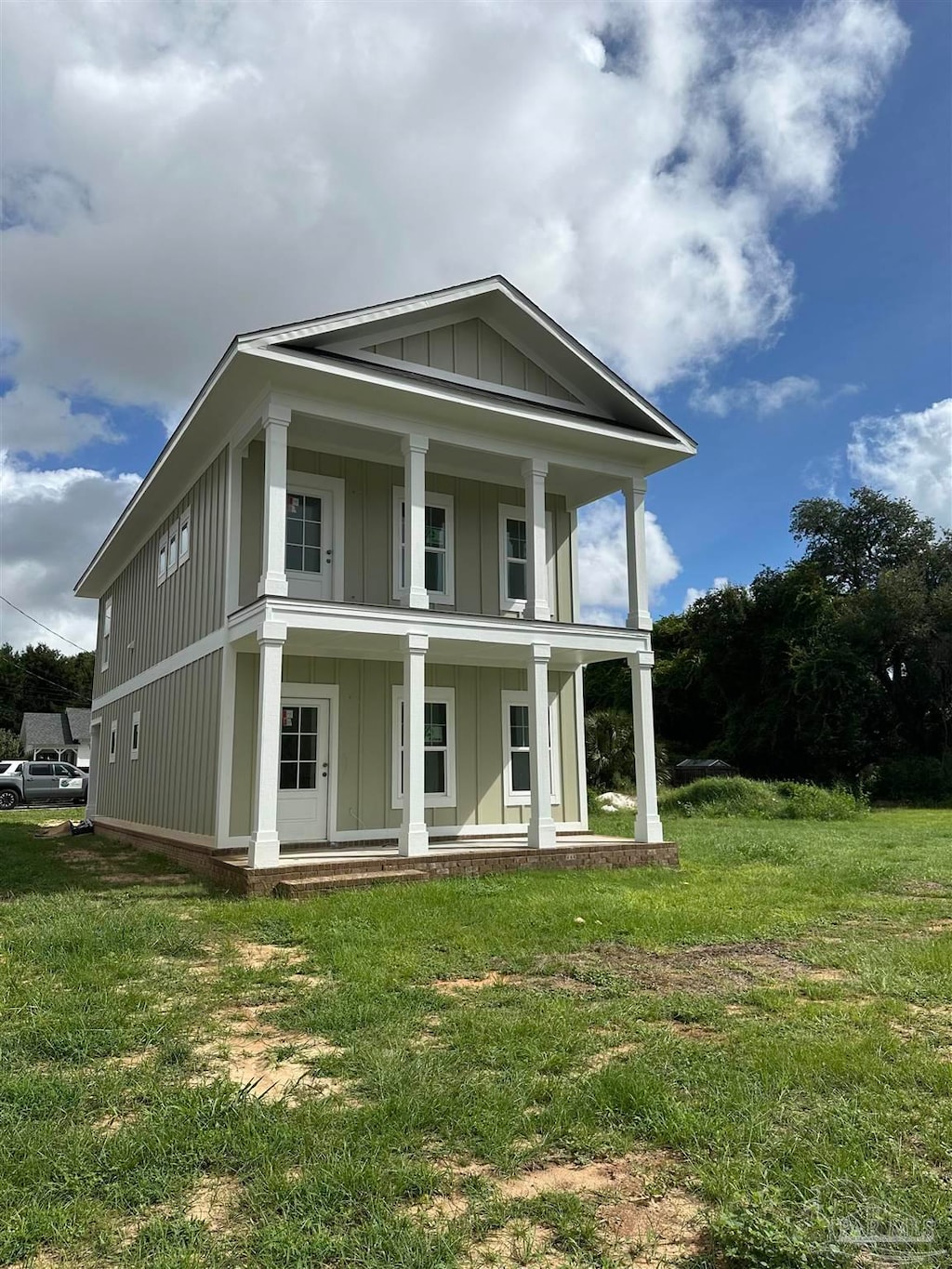 rear view of house featuring a lawn and a porch