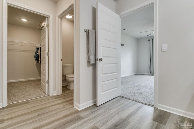 corridor with light colored carpet, baseboards, and light wood finished floors